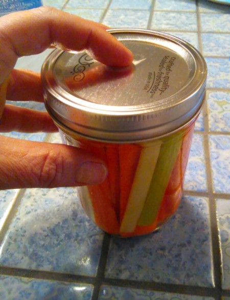 A canning jar with cut up carrots and celery with a lid.