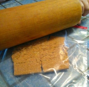 A rolling pin is being used to make graham cracker crumbs.