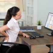 A woman at a computer with back pain.