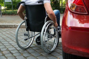 A man in a wheelchair getting into a car.