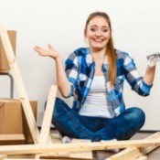 A woman putting together a piece of furniture with parts in her hands.
