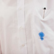 A ink pen that has stained the pocket of a white dress shirt.
