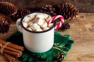 A hot cocoa with marshmallows and a candy cane stirrer.