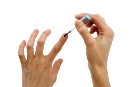 A woman painting white iodine on her nails to strengthen them.