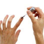 A woman painting white iodine on her nails to strengthen them.