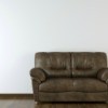 A brown leather sofa on a wood floor in front of a white wall.