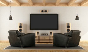 Two black armchairs facing a screen and speakers.