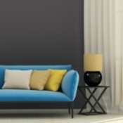 A blue couch on a dark gray wall.