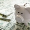 A piggy bank on top of many dollar bills.
