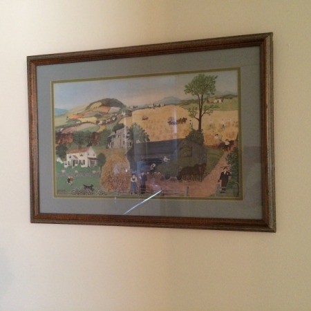 A large picture with a wooden frame, hanging on a wall.