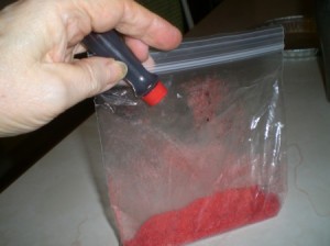adding red food coloring to sugar in Ziploc bag