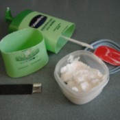 lotion bottle with bottom cut off and remaining product being put in a small container