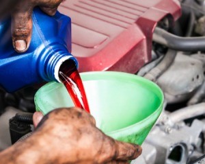 A mechanic pouring transmission fluid into a funnel.