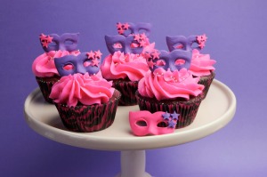 Cupcakes decorated with masquerade masks in purple and pink.