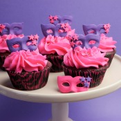 Cupcakes decorated with masquerade masks in purple and pink.