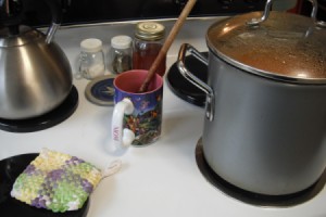 A coffee cup being used as a spoon rest on a stove.
