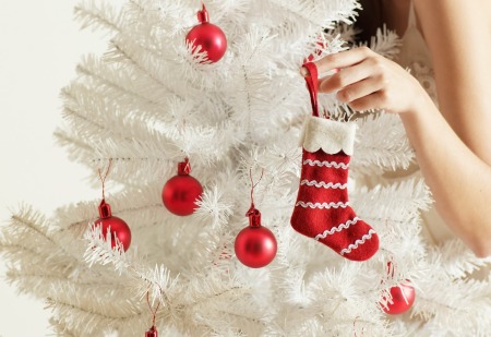 A white artificial Christmas tree with red ornaments.