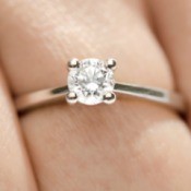 A diamond solitaire ring on a hand.