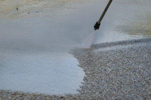 Using a pressure sprayer to clean paint off a driveway.