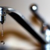 A kitchen faucet with a drip of water.