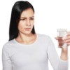 A woman looking concerned at a glass of water.