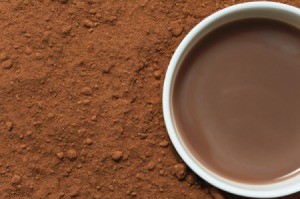 A cup of cocoa surrounded by cocoa powder.