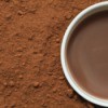 A cup of cocoa surrounded by cocoa powder.