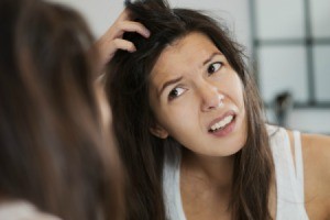 A woman noticing dandruff in her dark hair.