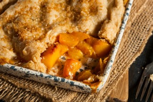A pan of peach cobbler with a serving removed.
