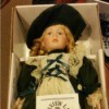 doll in dark dress with matching hat in box
