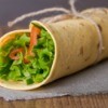 A tortilla sandwich wrap with lots of fresh veggies.