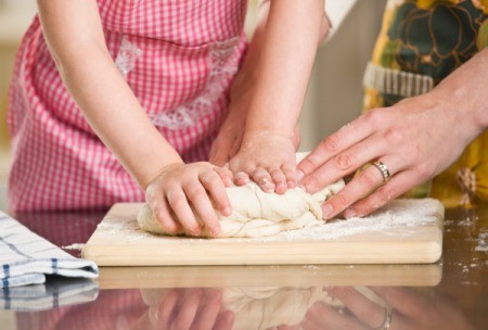 A woman kneading bread with a child.