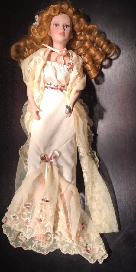 Doll with curly hair and a white formal dress.