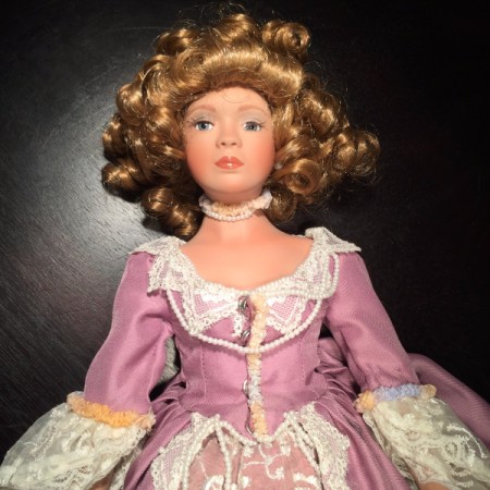 Doll with curled hair and a white and pink dress.
