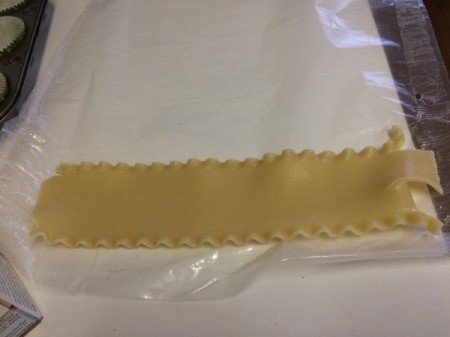 Rolling cooked noodles in wax paper.