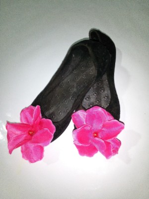 A pair of black dress shoes with flowers on the toes.