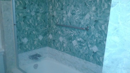 Bathroom tub enclosure with a tile wall covered with contact paper.