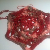 A dishcloth made from croched yarn in a flower shape.