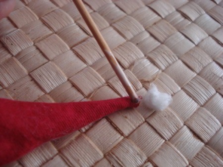 Spool Santa Ornament - gluing a tiny ball of cotton to the tip of Santa's hat using a small wooden stick