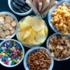 A bunch of bowls of salty snack foods.