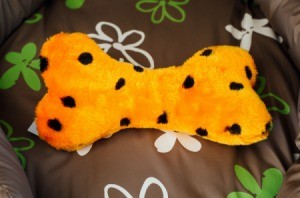 An orange and black bone shaped dog toy with a squeaker inside.