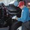 A diesel mechanic checking a trucks oil.
