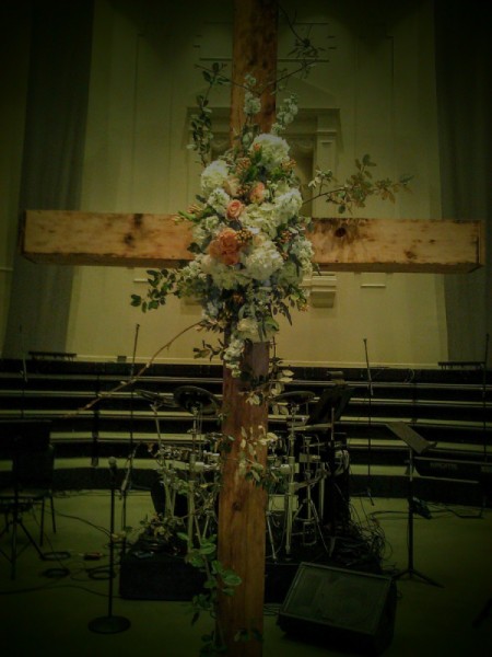 A cross adorned with flowers for a wedding.