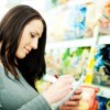 A woman grocery shopping looking at her organized shopping list.