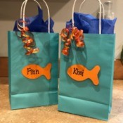 Goldfish Party Treat Bags - aqua gift bags with orange goldfish cutouts and ribbon as decorations