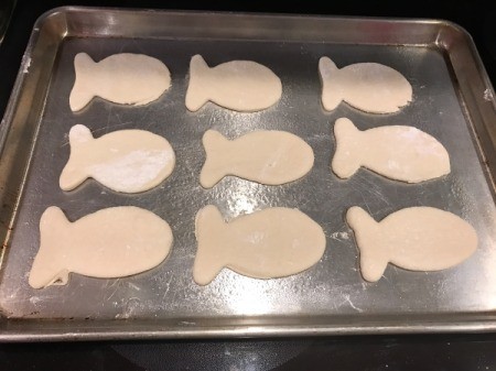 Goldfish Shaped Mini Pizzas - 9 fish pizzas on baking sheet ready to add sauce