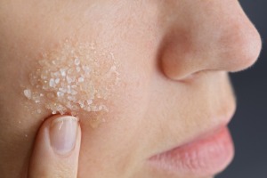 A woman using a sea salt facial scrub.