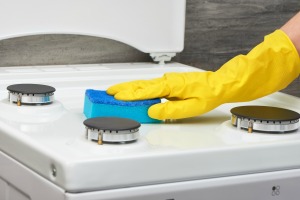 Hand wiping stove with a sponge.