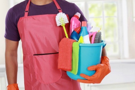 Man in an apron with a bucket of cleaning supplies.