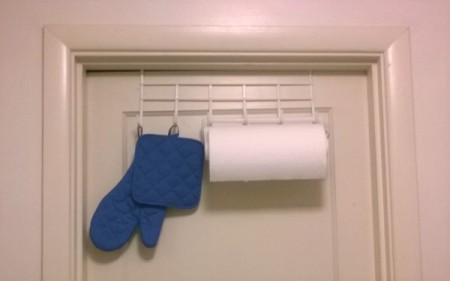An over the door hook with paper towels and hotpads.